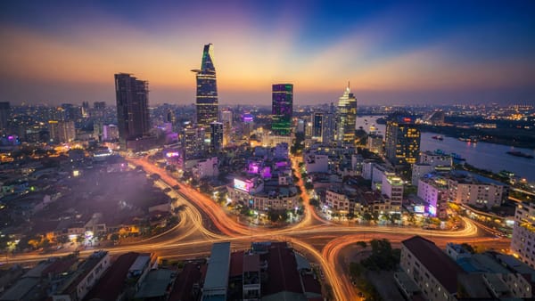 Ho Chi Minh City District 1 skyline at neon hour with Bitexco Tower and motorbike light trails